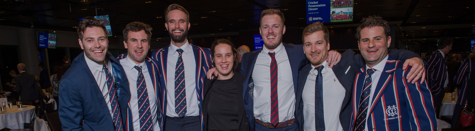 A group of players stand together for a photo. Some are wearing their MCC striped blazers.