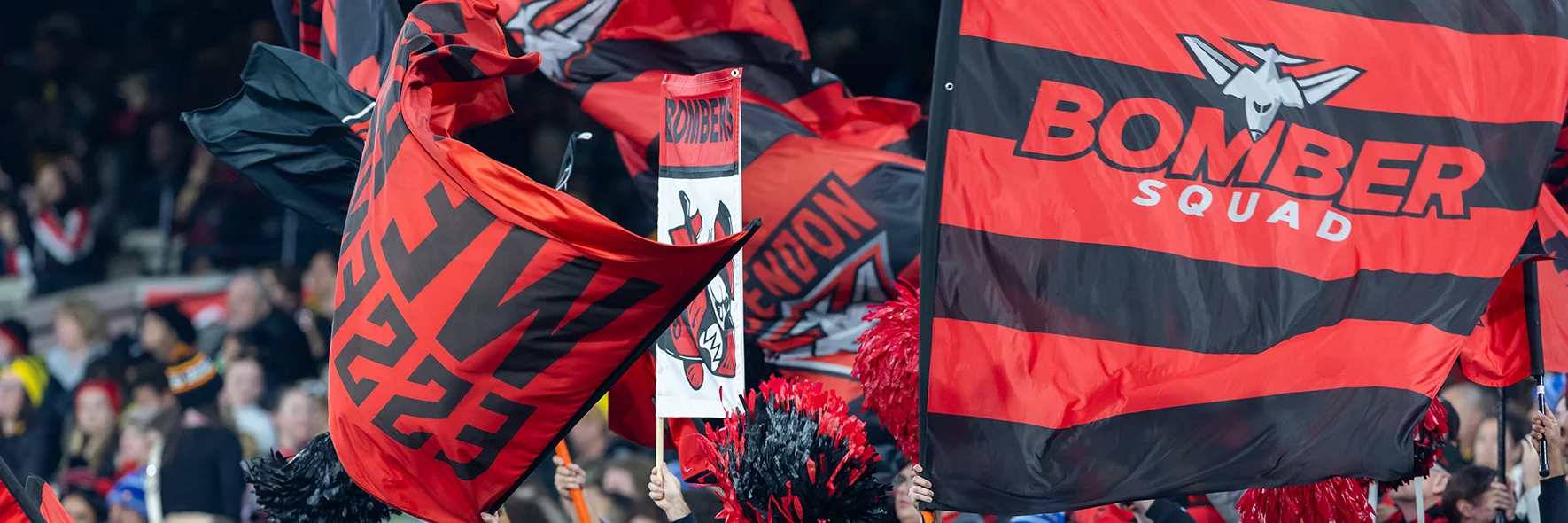 Essendon cheer squad with red and black Bombers flags