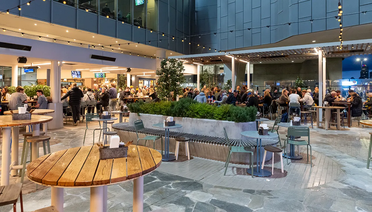 Patrons seated outdoors with cafe tables and hanging lights.