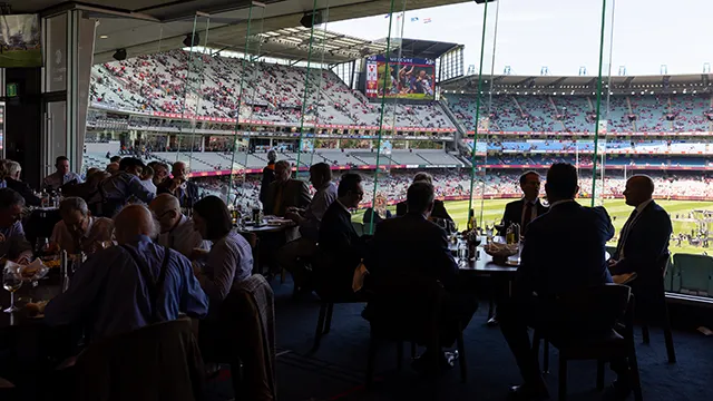 Patrons dining next to large windows with a view onto the MCG turf and seating