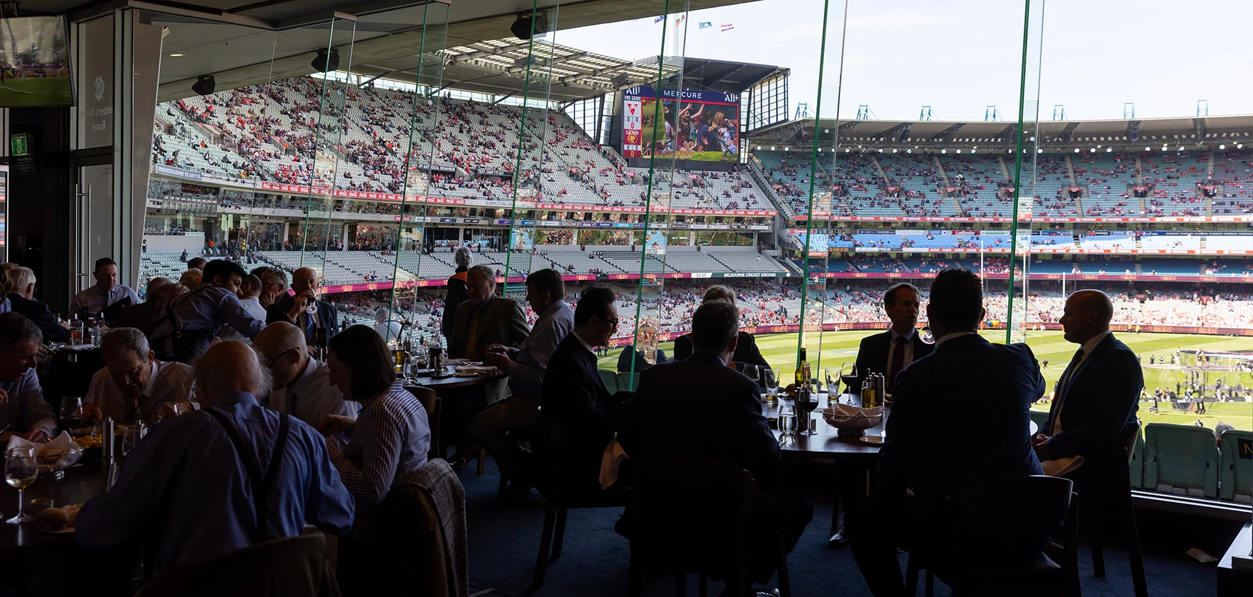 Patrons in Members' Dining Room with AFL stadium view