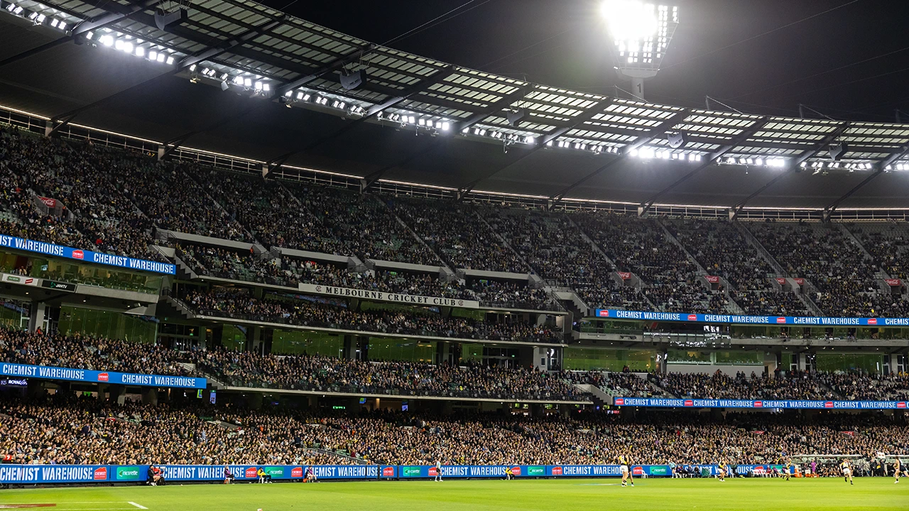 A packed Members' Reserve under lights at night AFL match
